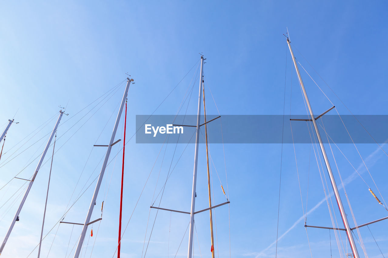 Yacht masts without sails against blue sky