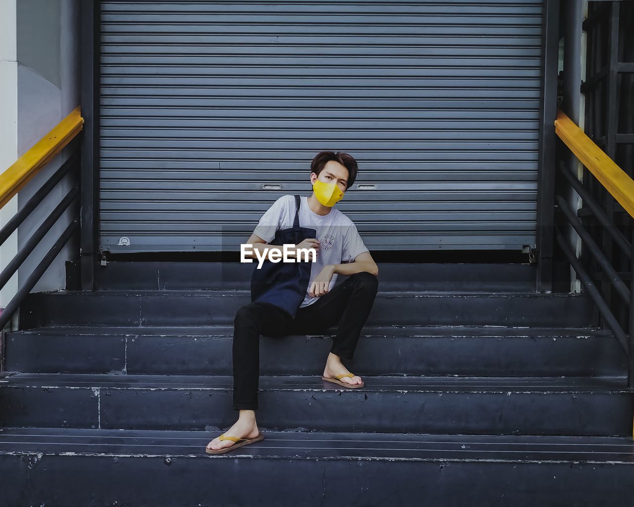 Full length of man wearing mask sitting on staircase