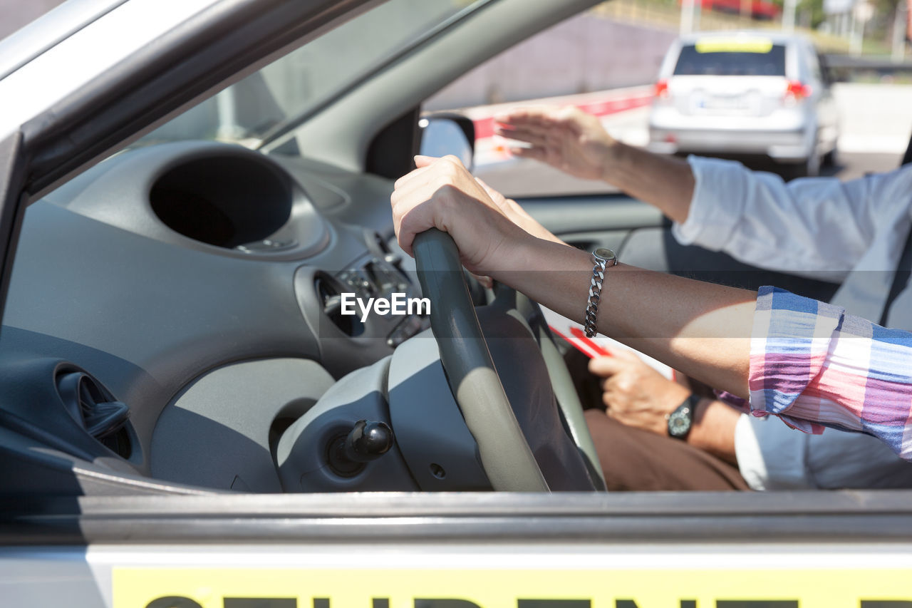 Cropped hands of woman driving car in city