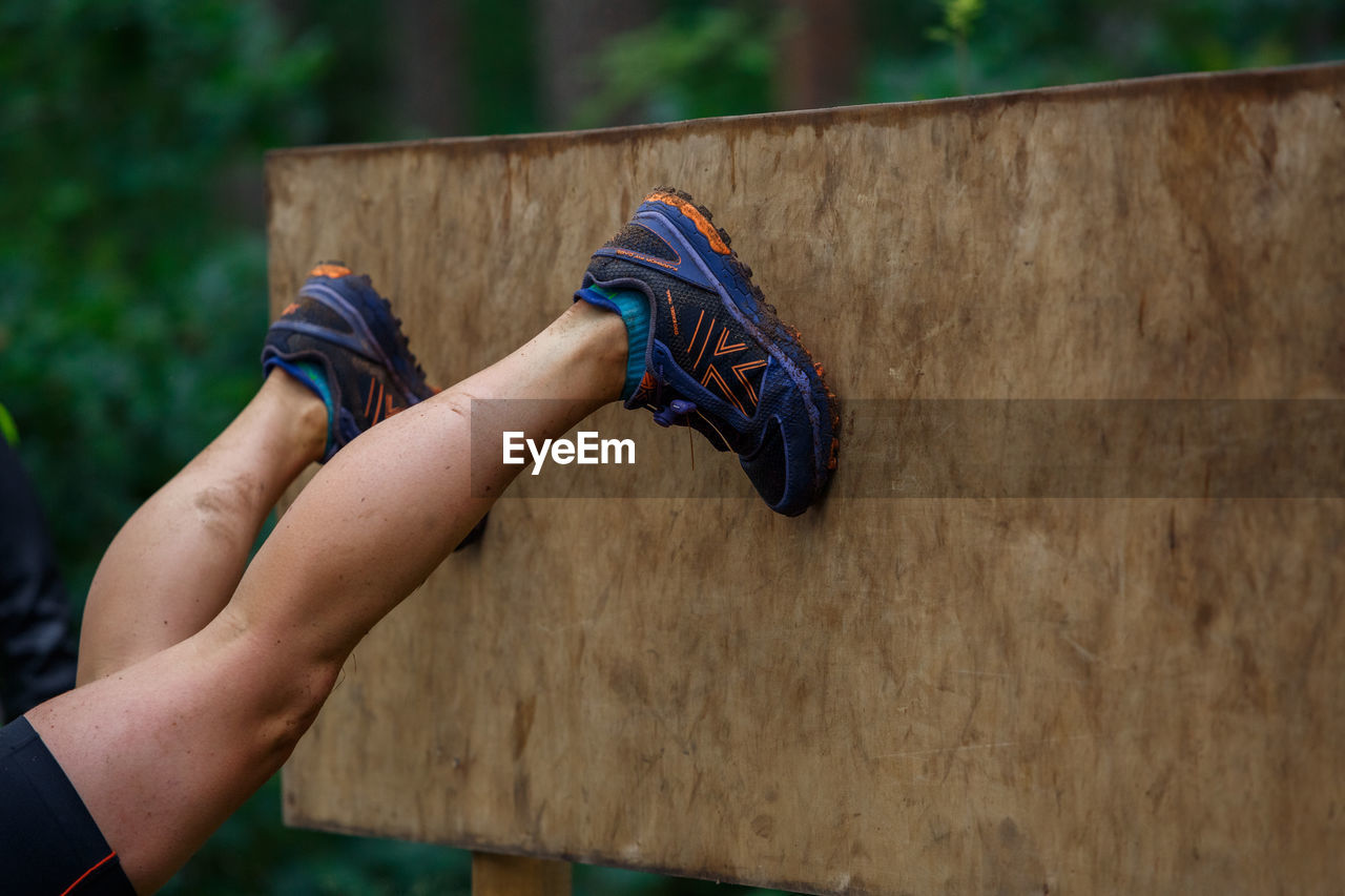 LOW SECTION OF PERSON HOLDING ROPE AGAINST WOOD