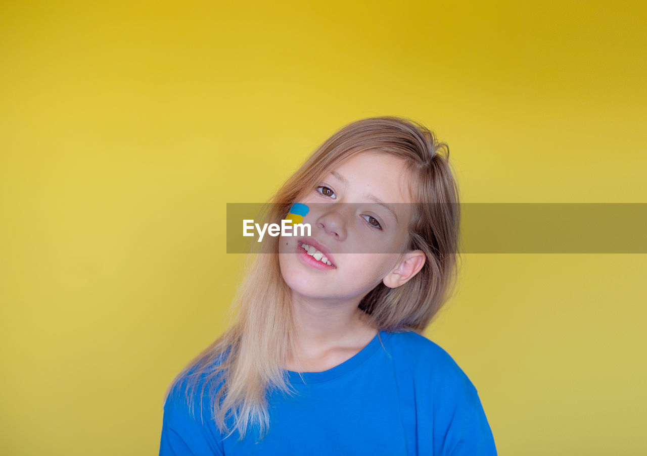 Portrait of young woman against yellow background