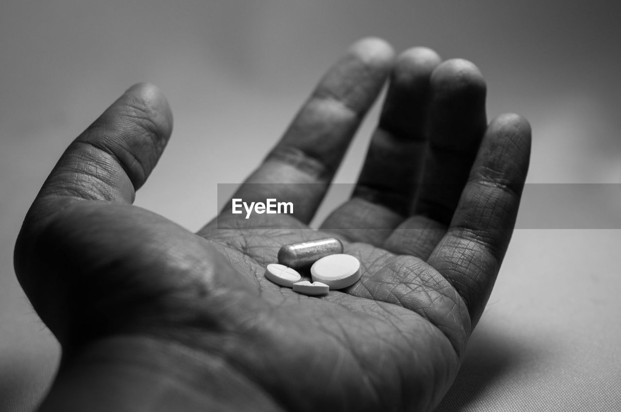 Close-up of hand holding pills at table