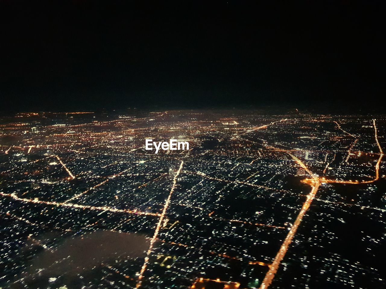 HIGH ANGLE VIEW OF ILLUMINATED CITY BUILDINGS AGAINST SKY AT NIGHT