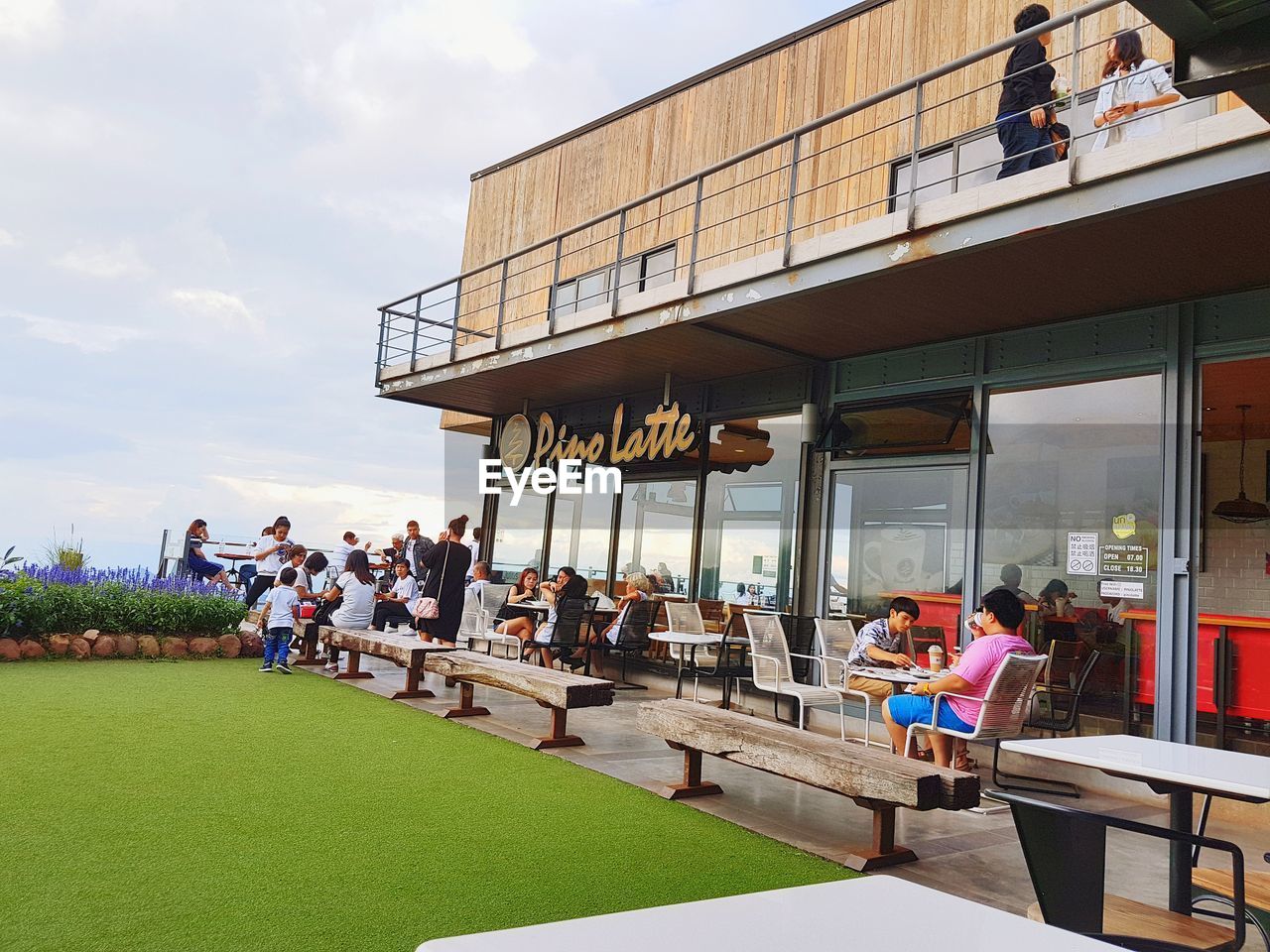 PEOPLE SITTING IN CAFE AGAINST SKY