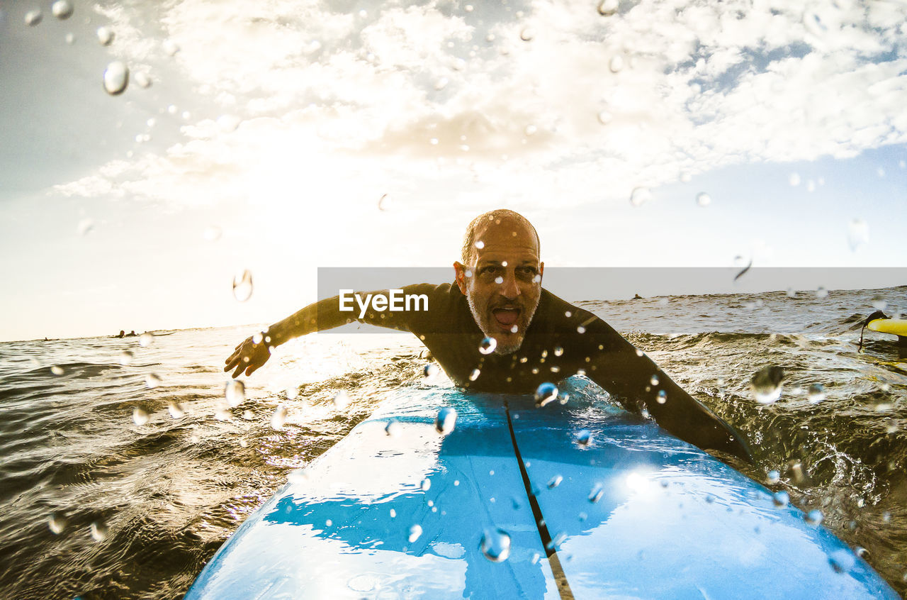 Mature man surfing in sea against sky