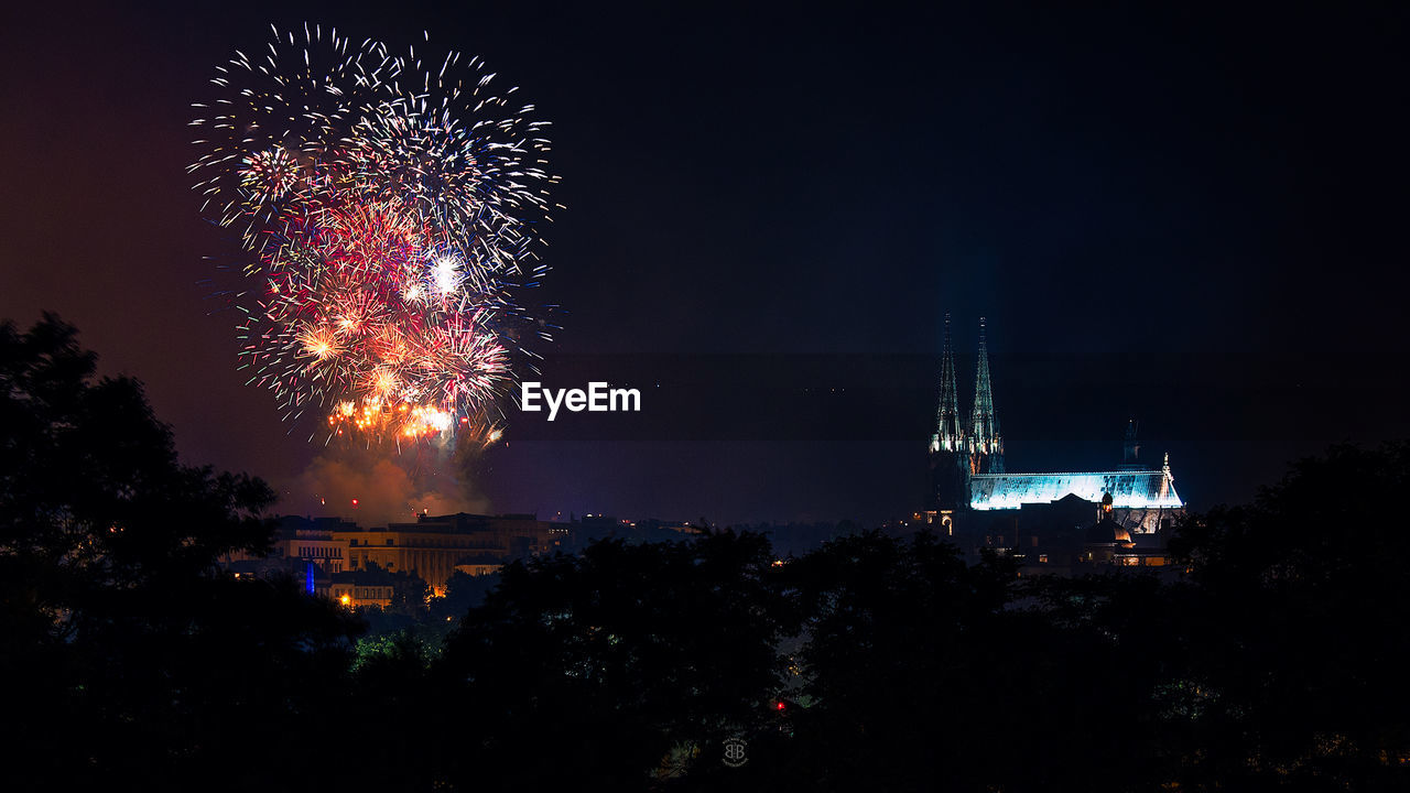 Illuminated fireworks by historic cathedral against sky at night