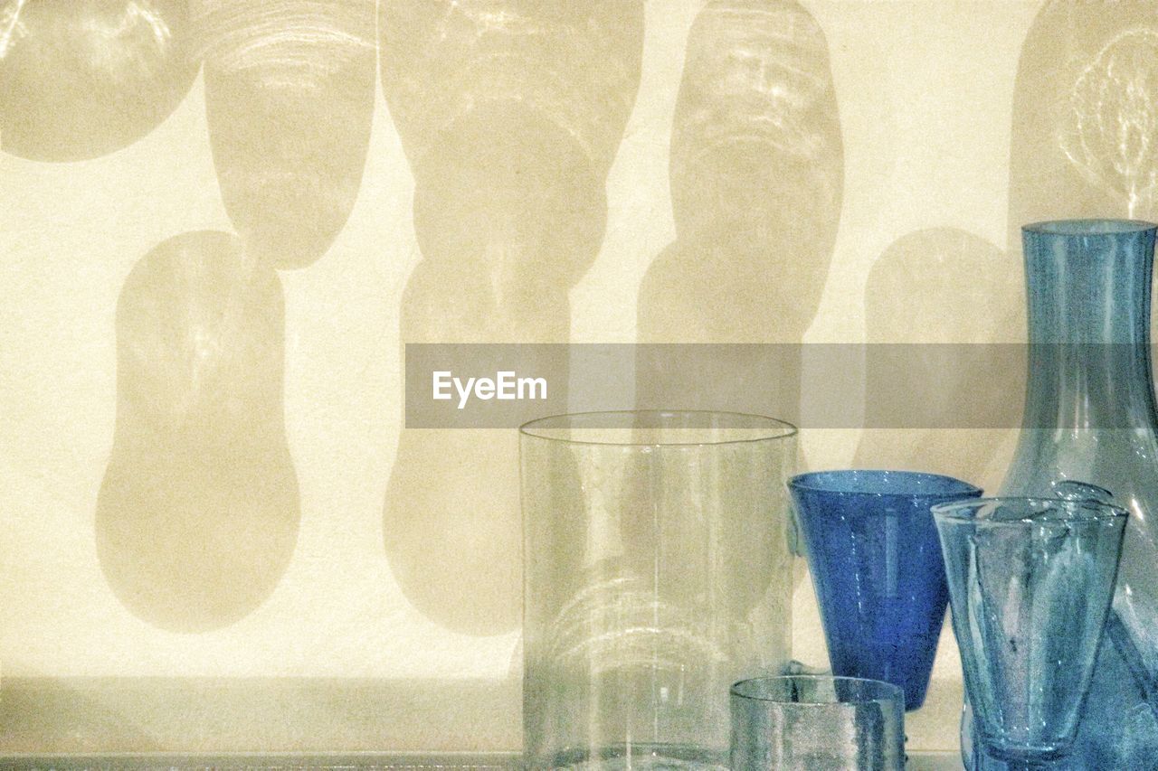 Close-up of glass containers against wall
