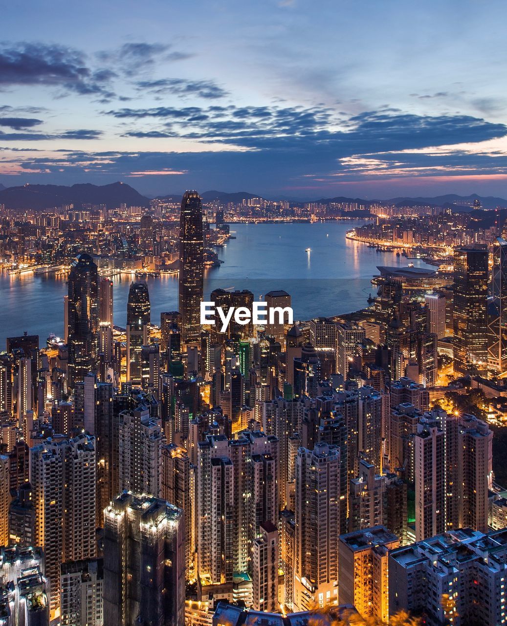 High angle view of illuminated city by sea against sky