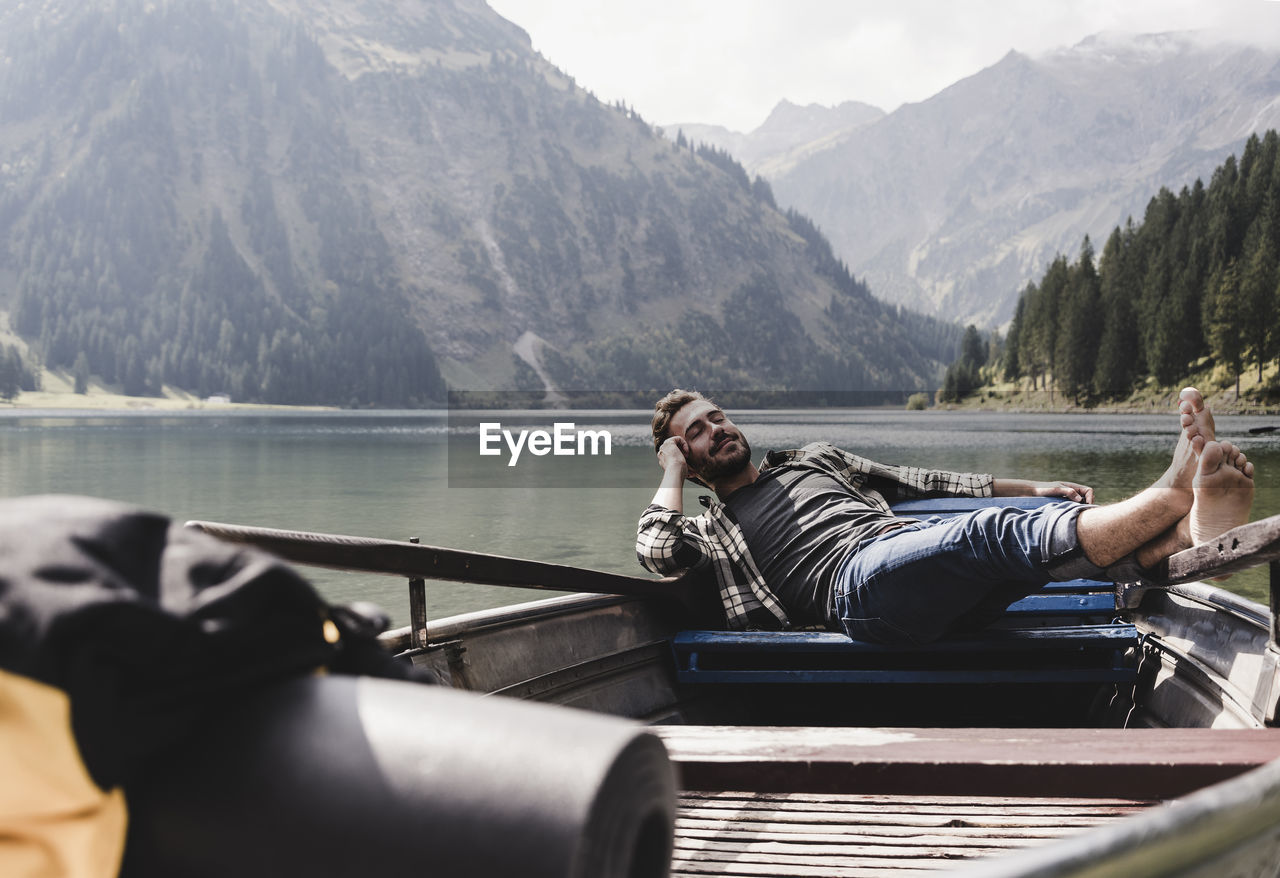 Austria, tyrol, alps, relaxed man in boat on mountain lake