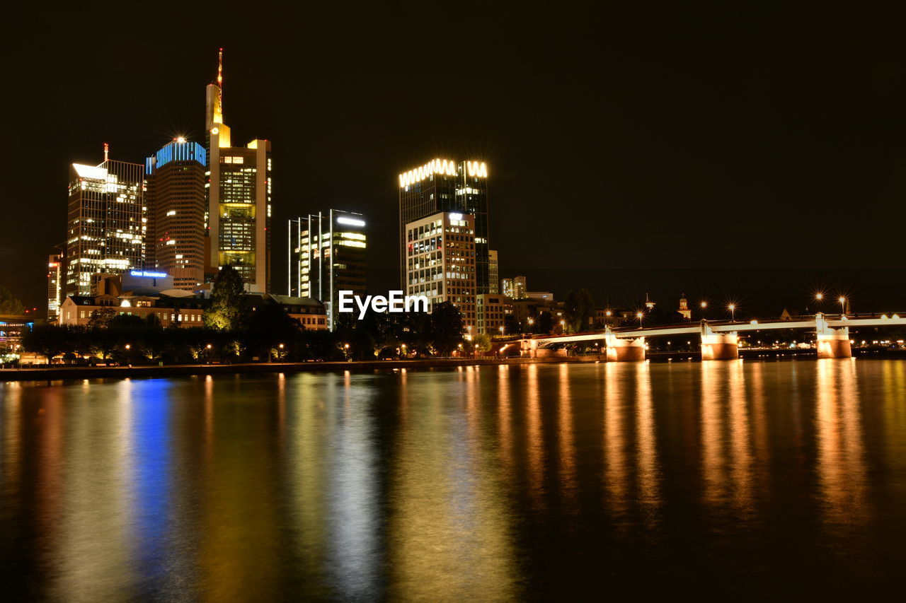 ILLUMINATED CITY BUILDINGS AT WATERFRONT