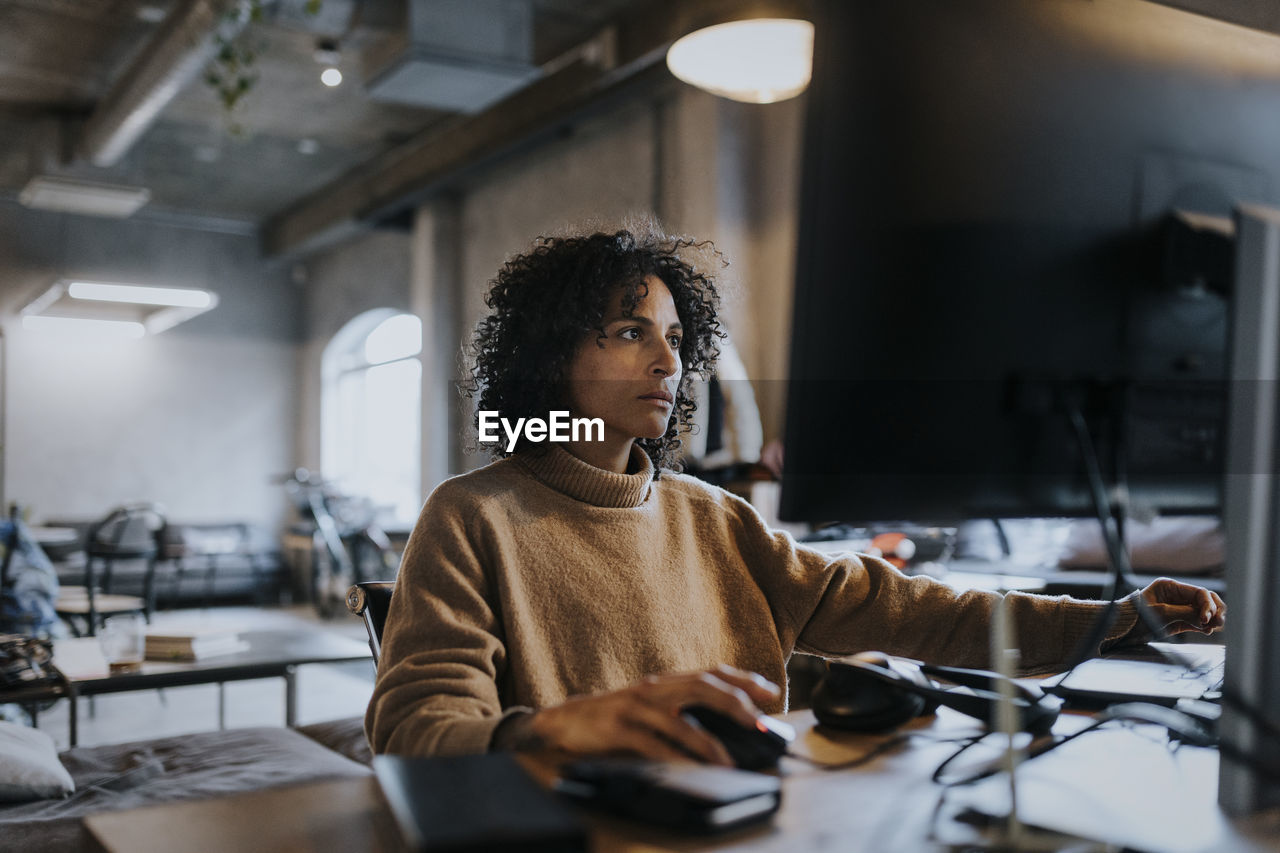 Female programmer concentrating while working on computer at desk in office