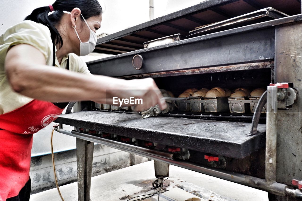 Woman preparing food in oven at restaurant