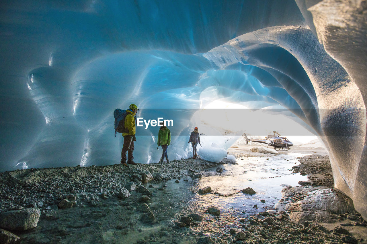 Adventure guide shows two female clients into a glacial cave.