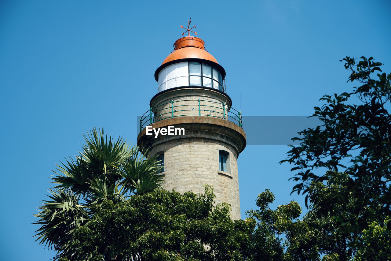 LOW ANGLE VIEW OF LIGHTHOUSE BY TREES AGAINST SKY
