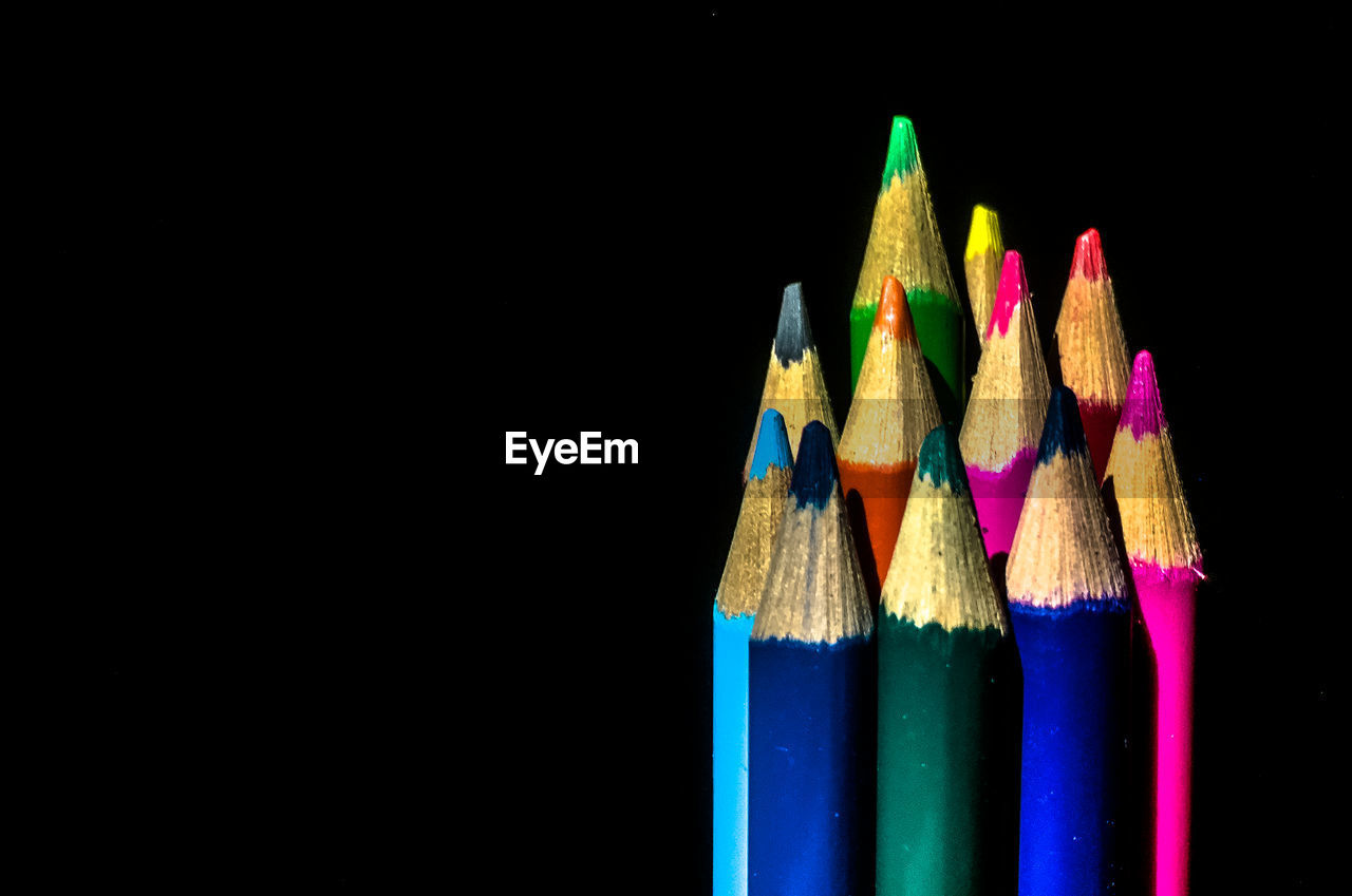 CLOSE-UP OF MULTI COLORED PENCILS ON BLACK BACKGROUND