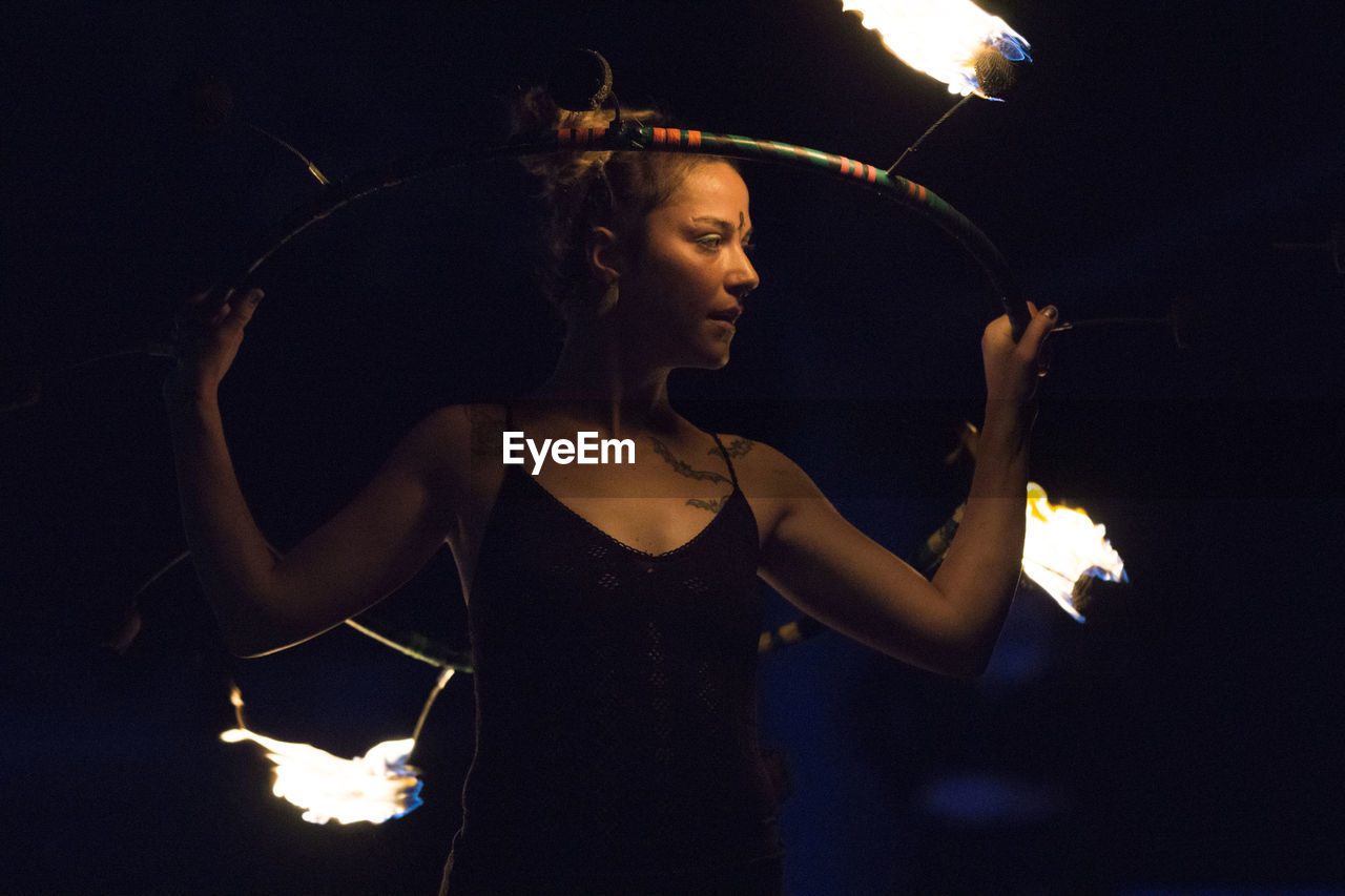 Woman holding burning ring while performing at night