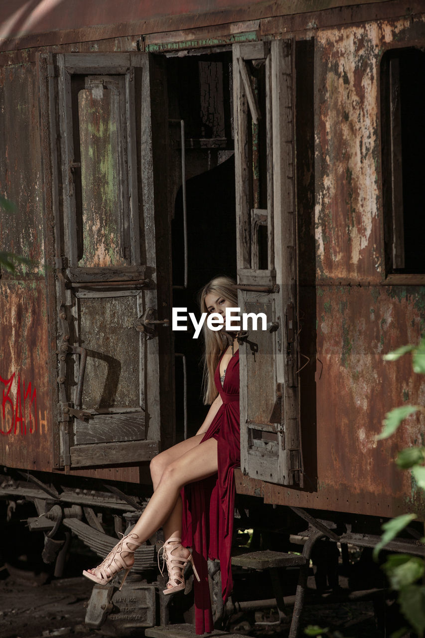 Portrait woman sitting on abandoned train doorway