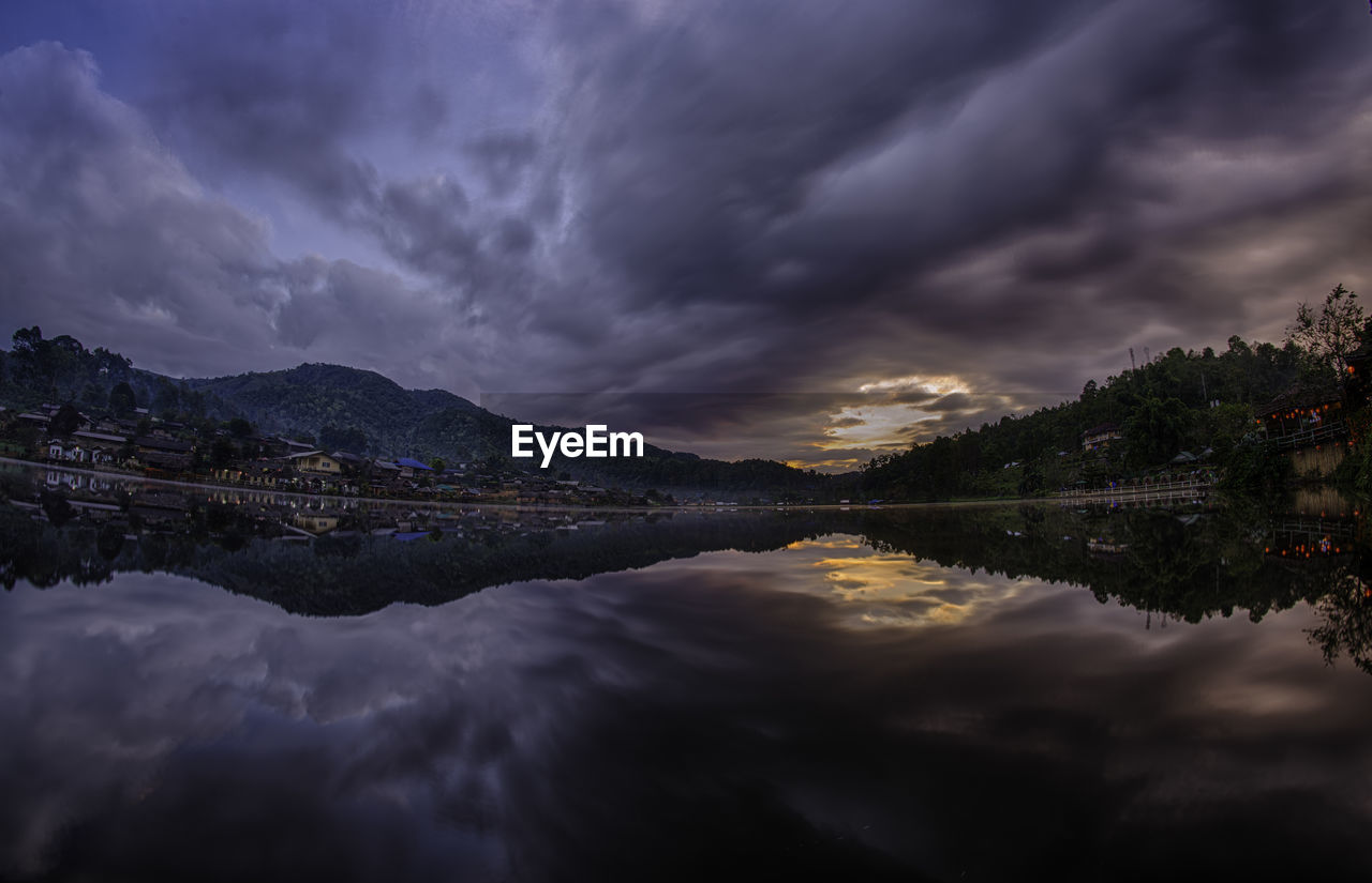 Scenic view of lake and mountains against storm clouds