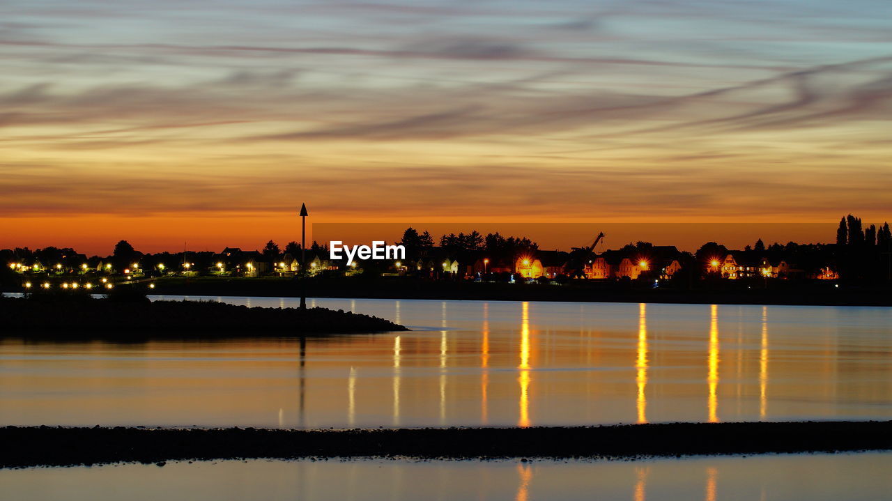 Scenic view of river against cloudy sky at sunset