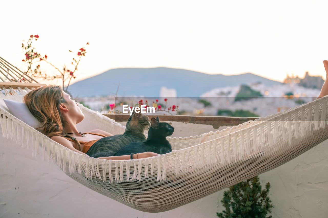 YOUNG WOMAN RELAXING AGAINST SKY