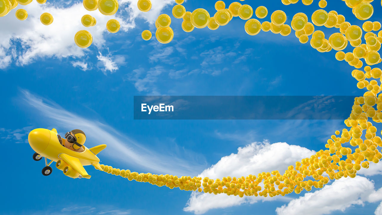 LOW ANGLE VIEW OF YELLOW BALLOONS IN WATER AGAINST SKY
