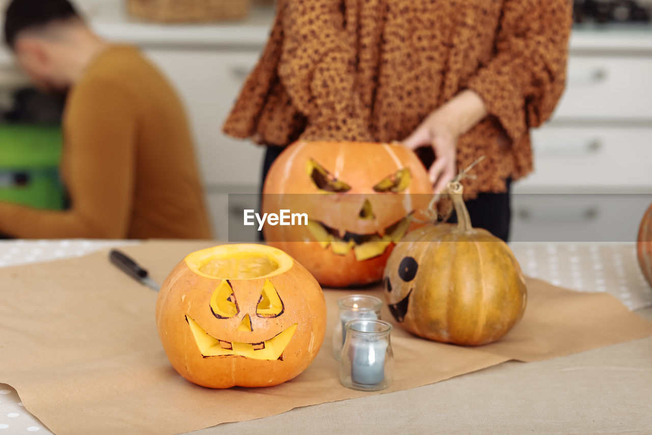 midsection of woman holding jack o lantern on table