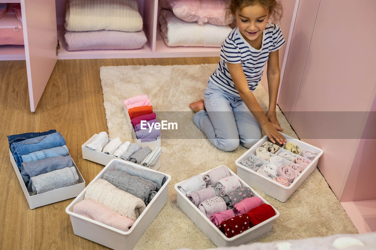 High angle view of girl arranging clothes in container