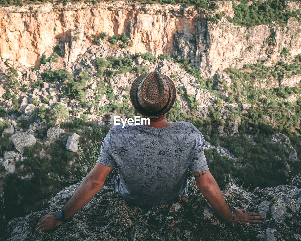 Rear view of man sitting on rock formation