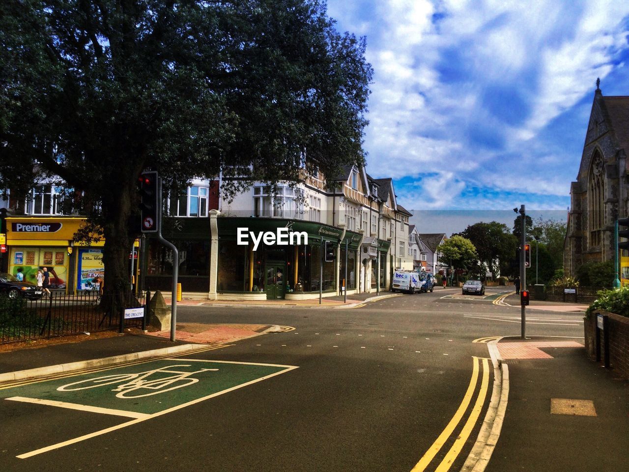 Street by buildings and trees against sky