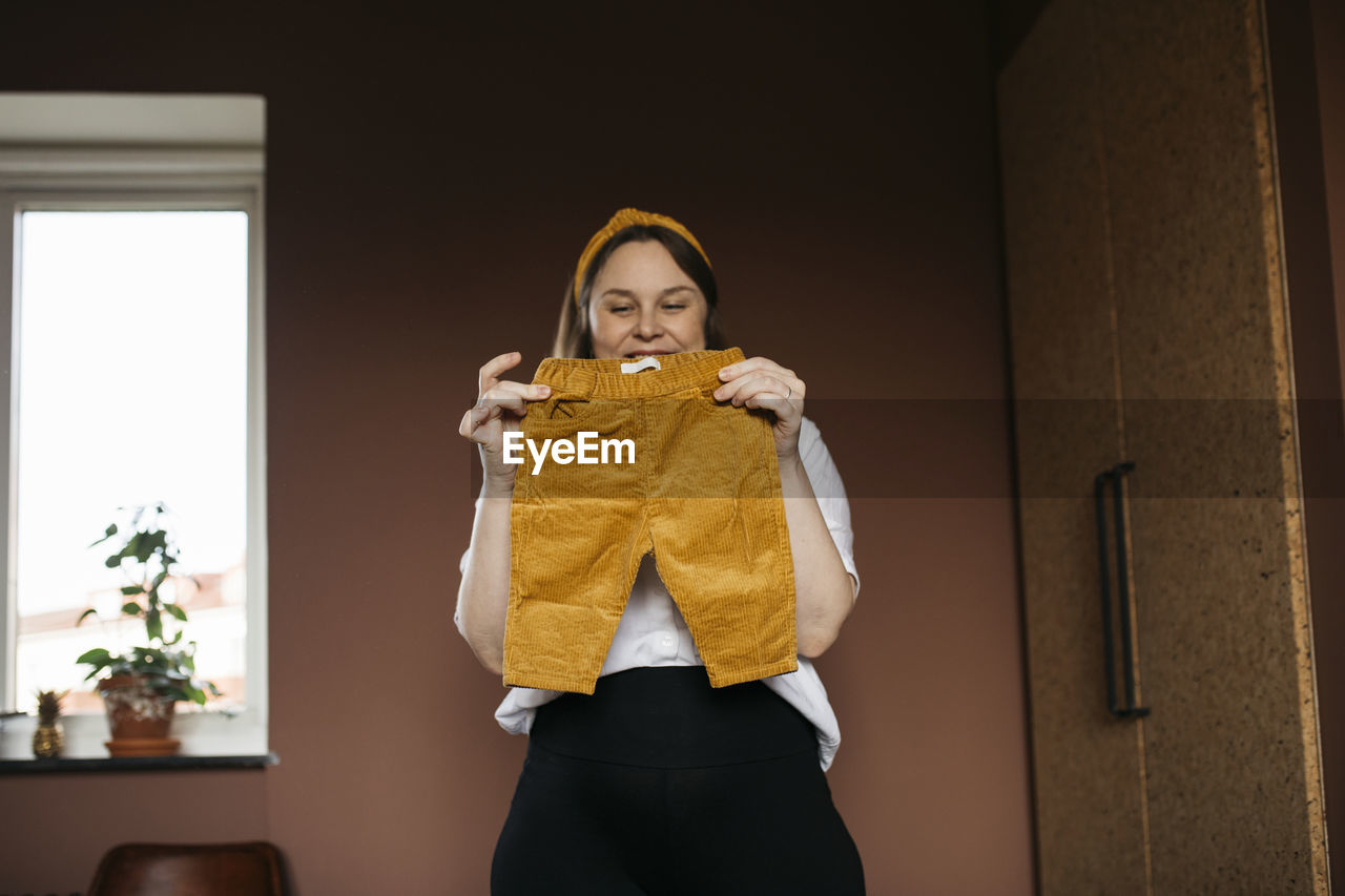 Woman in bedroom holding baby trousers