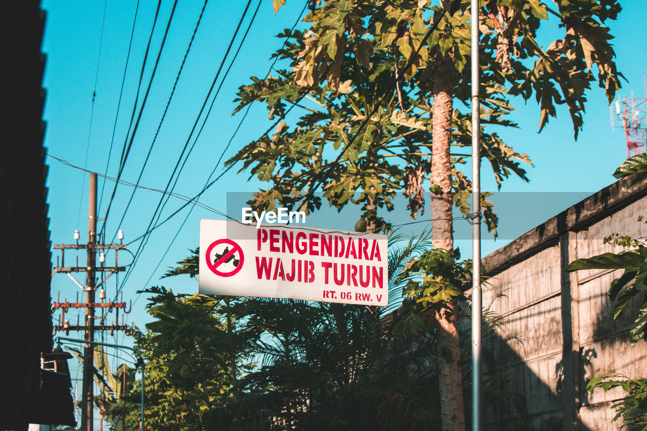 LOW ANGLE VIEW OF INFORMATION SIGN AGAINST TREES