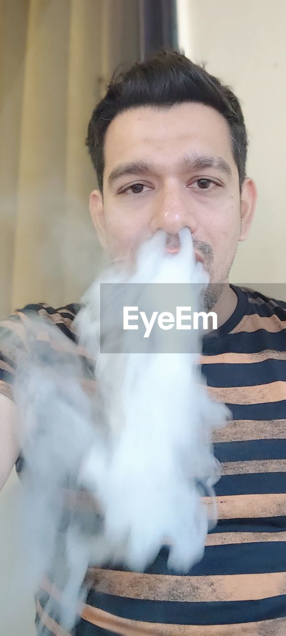 smoke, one person, men, adult, smoking, portrait, front view, person, looking at camera, indoors, holding, human head, human hair, nose, activity, smoking issues, steam, waist up, brown hair, lifestyles, mammal, beard, cigarette, headshot, human face, young adult, facial hair
