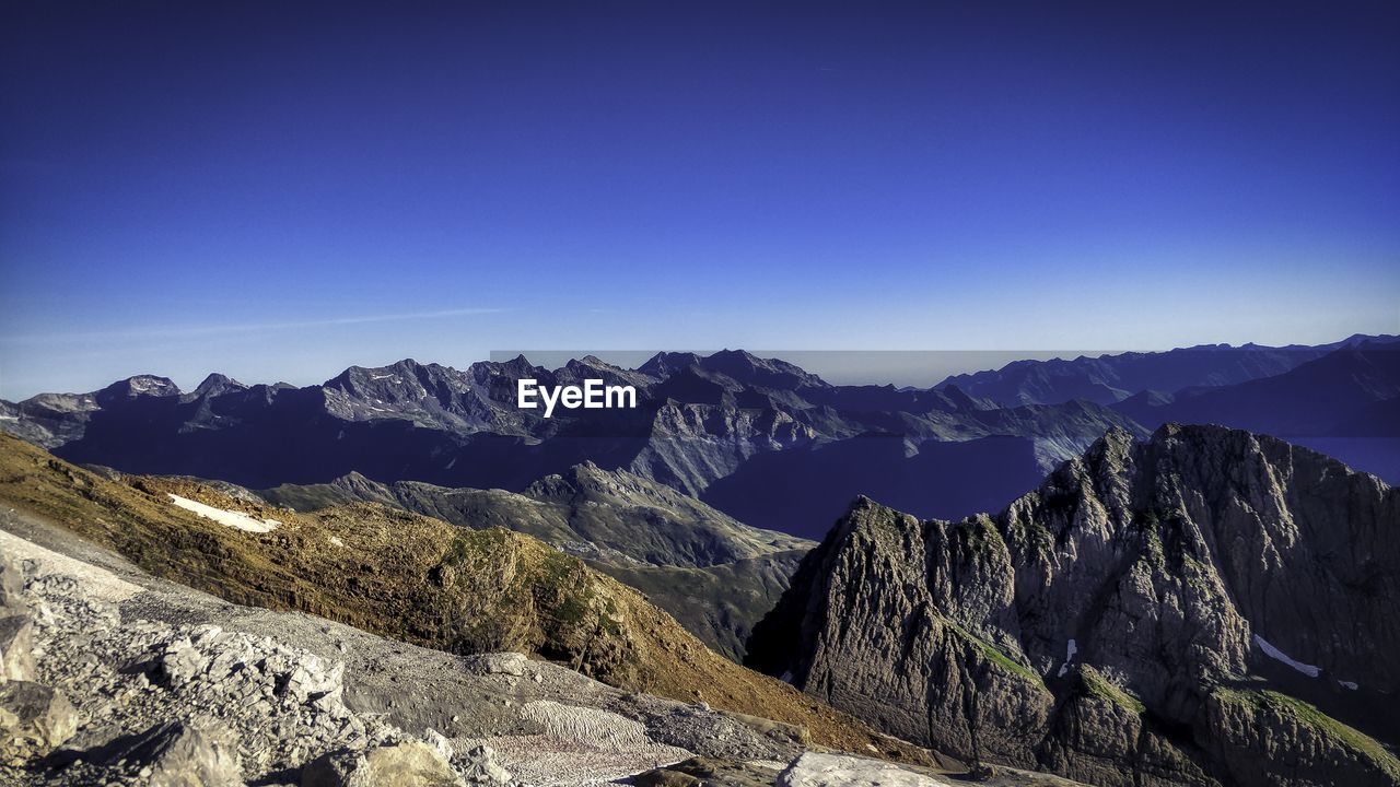 Scenic view of snowcapped mountains against clear blue sky