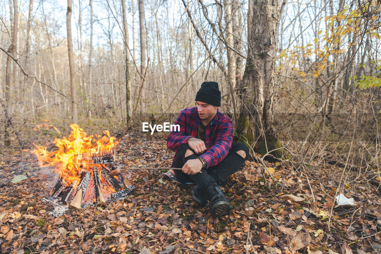 Man roasting food in campfire at forest