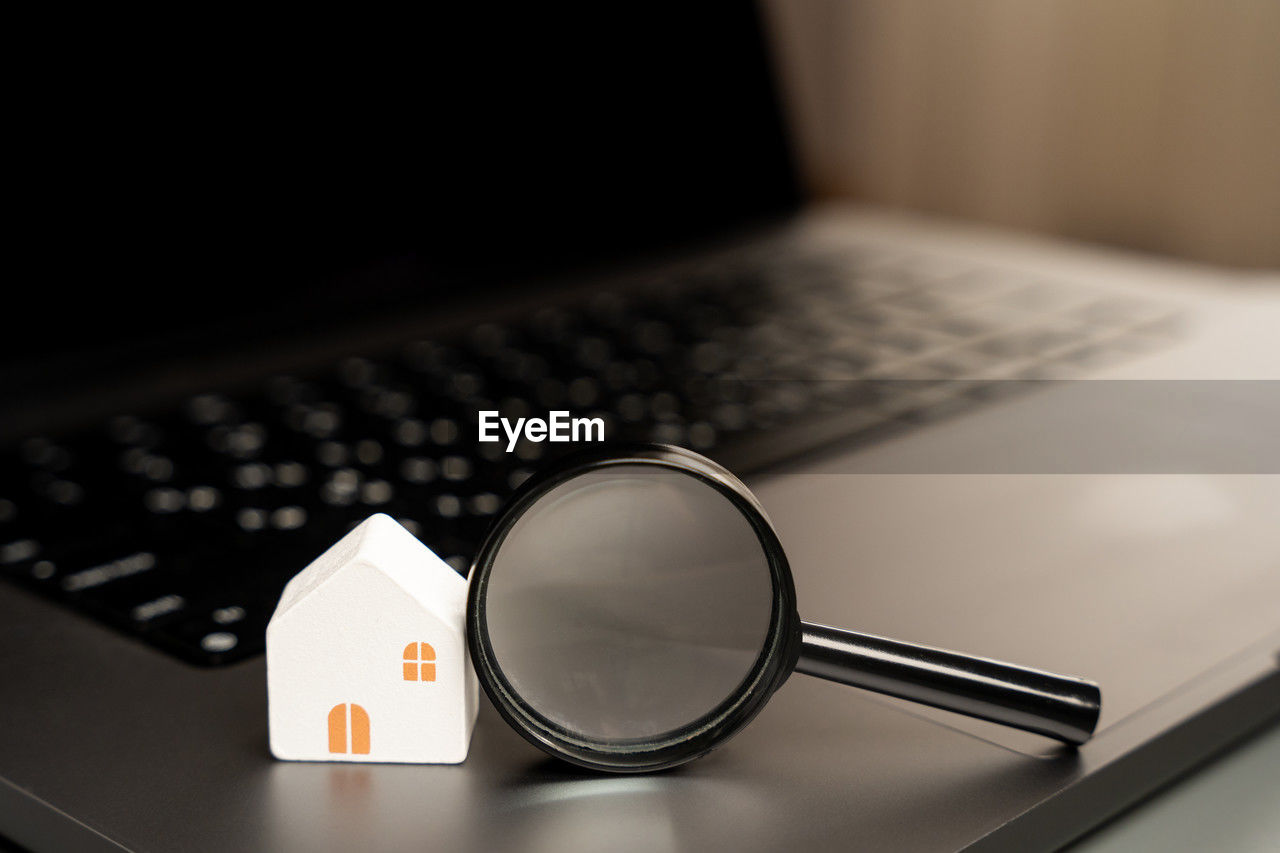 House and magnifying glass on laptop keyboard. the concept of searching for housing via the internet