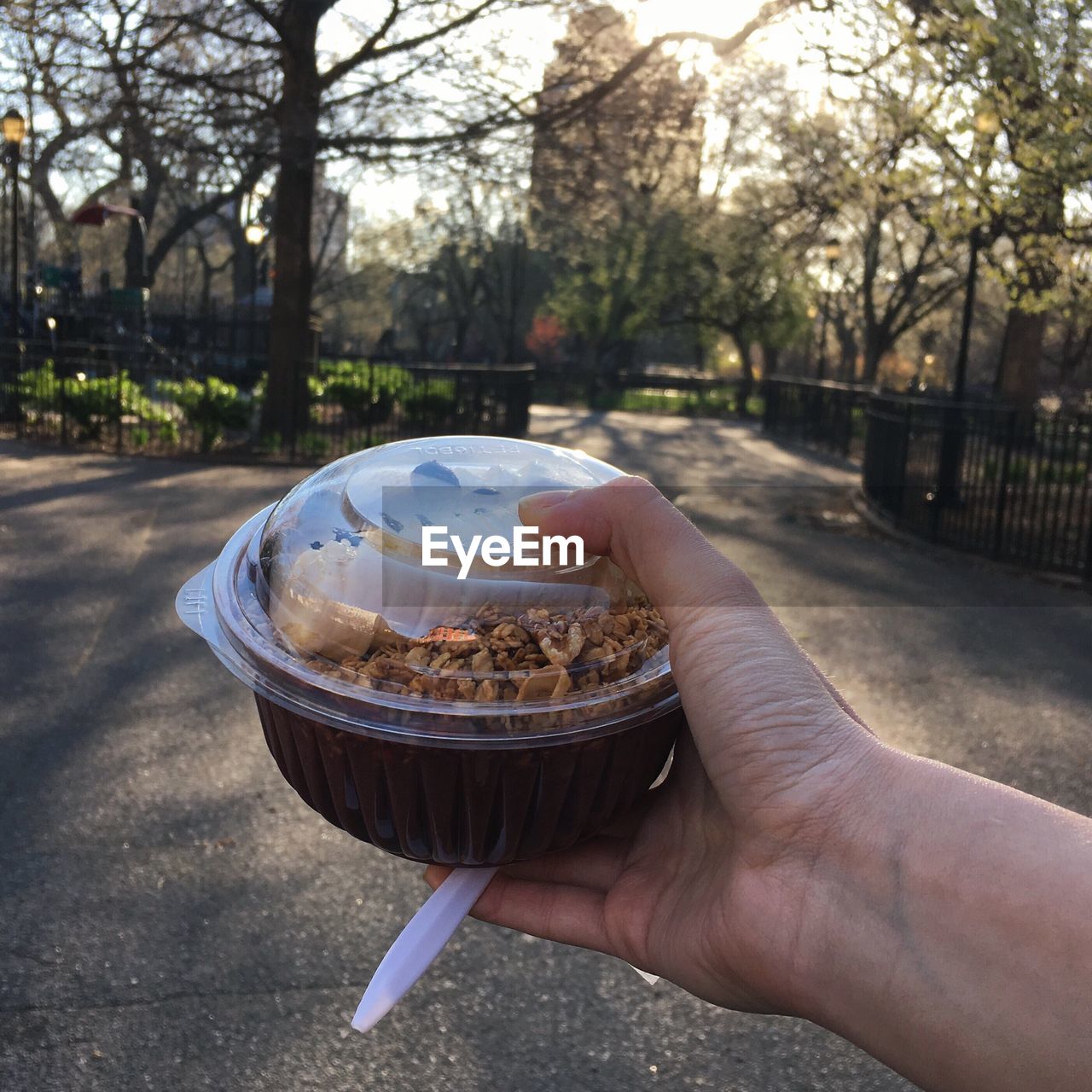 Cropped hand holding food in plastic container on street