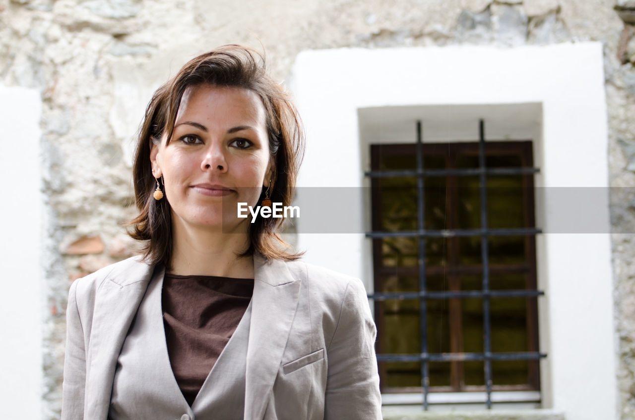 Portrait of mature woman standing against building