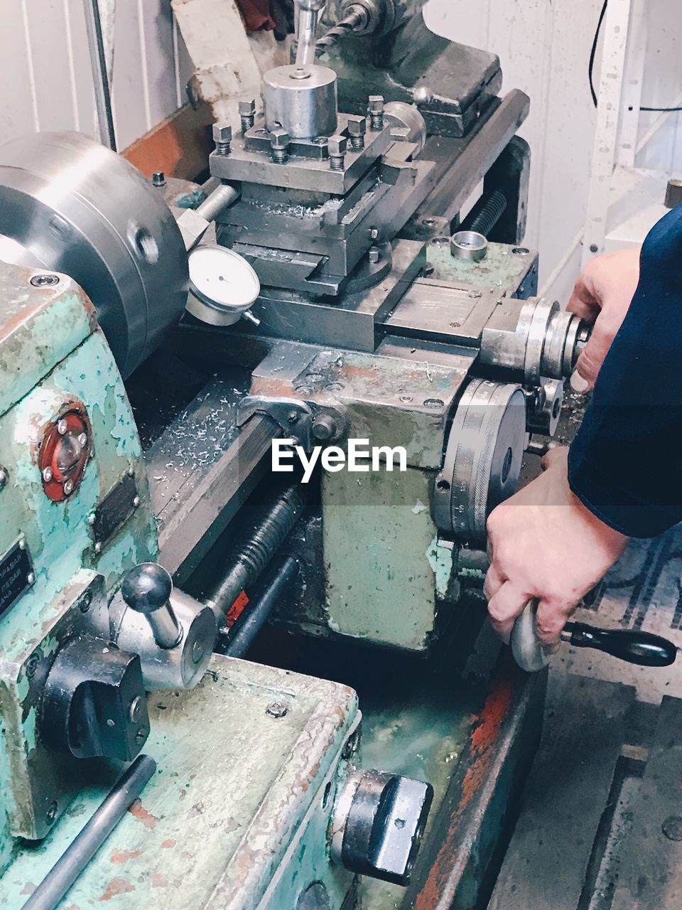 Cropped hands of man holding machinery in factory