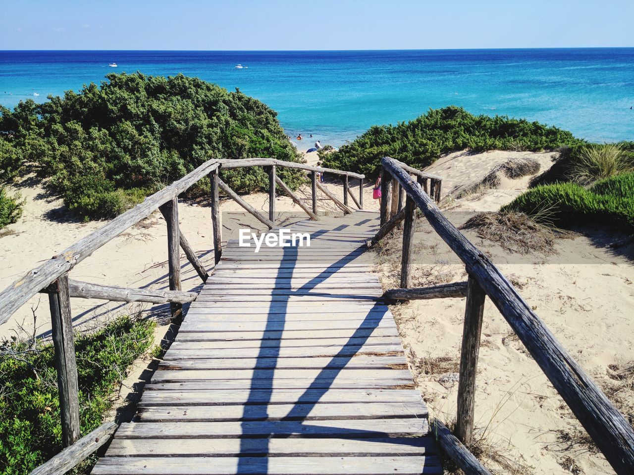 Wooden railing on beach against sky