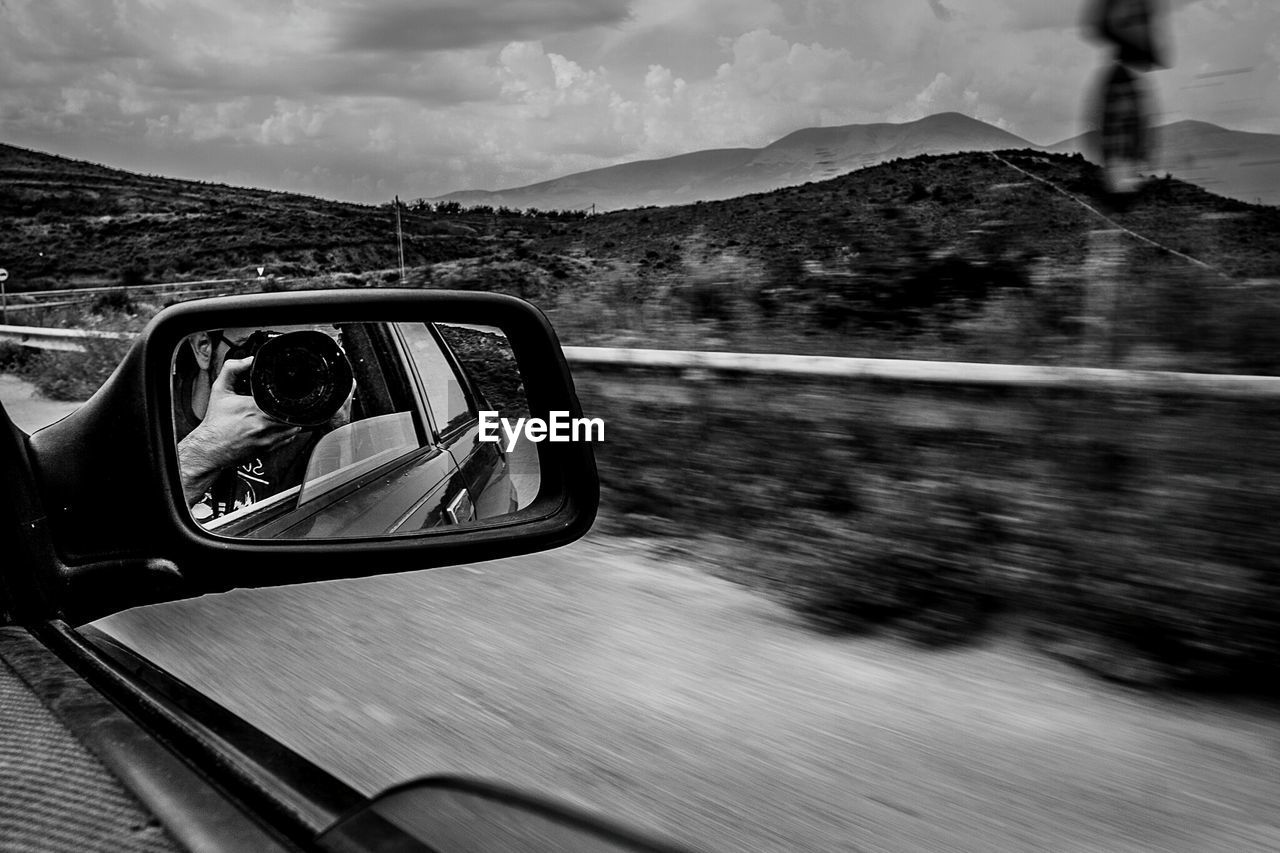 Reflection of man in side view mirror of car