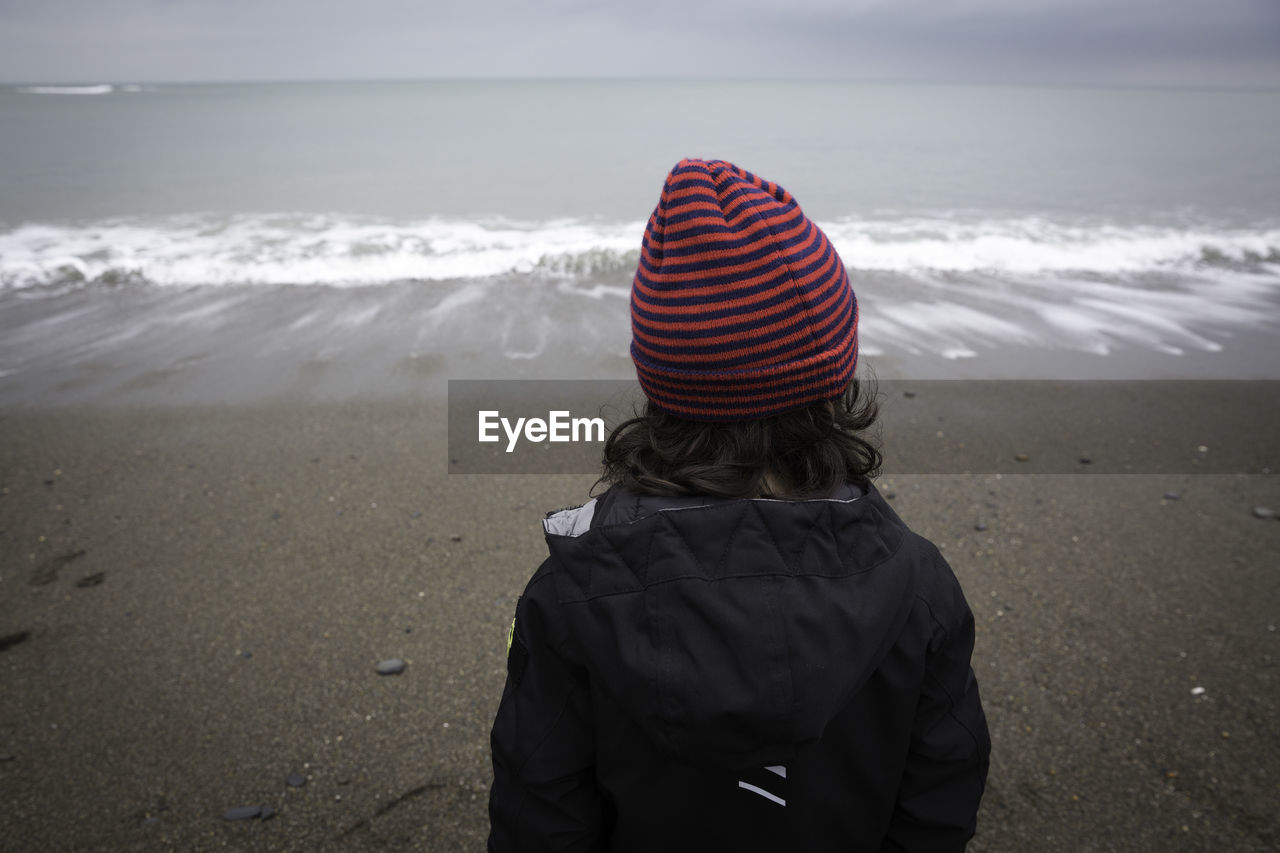 Rear view of girl standing at beach