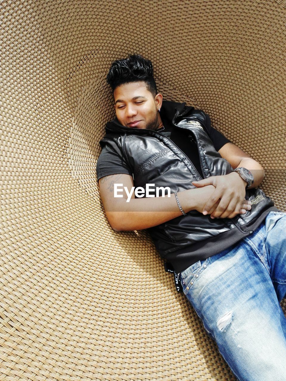 High angle view of young man relaxing on wicker seat