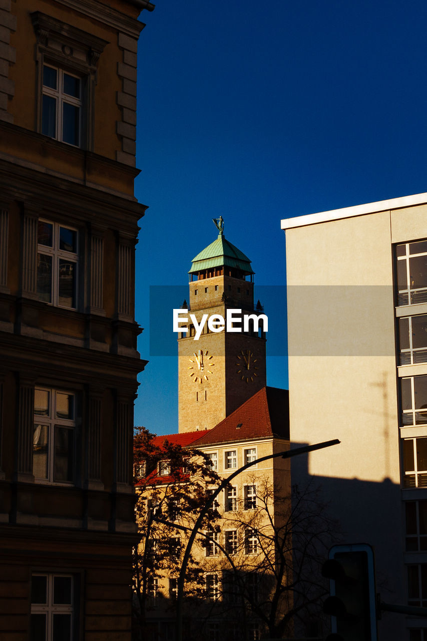 LOW ANGLE VIEW OF CLOCK TOWER IN CITY AGAINST SKY