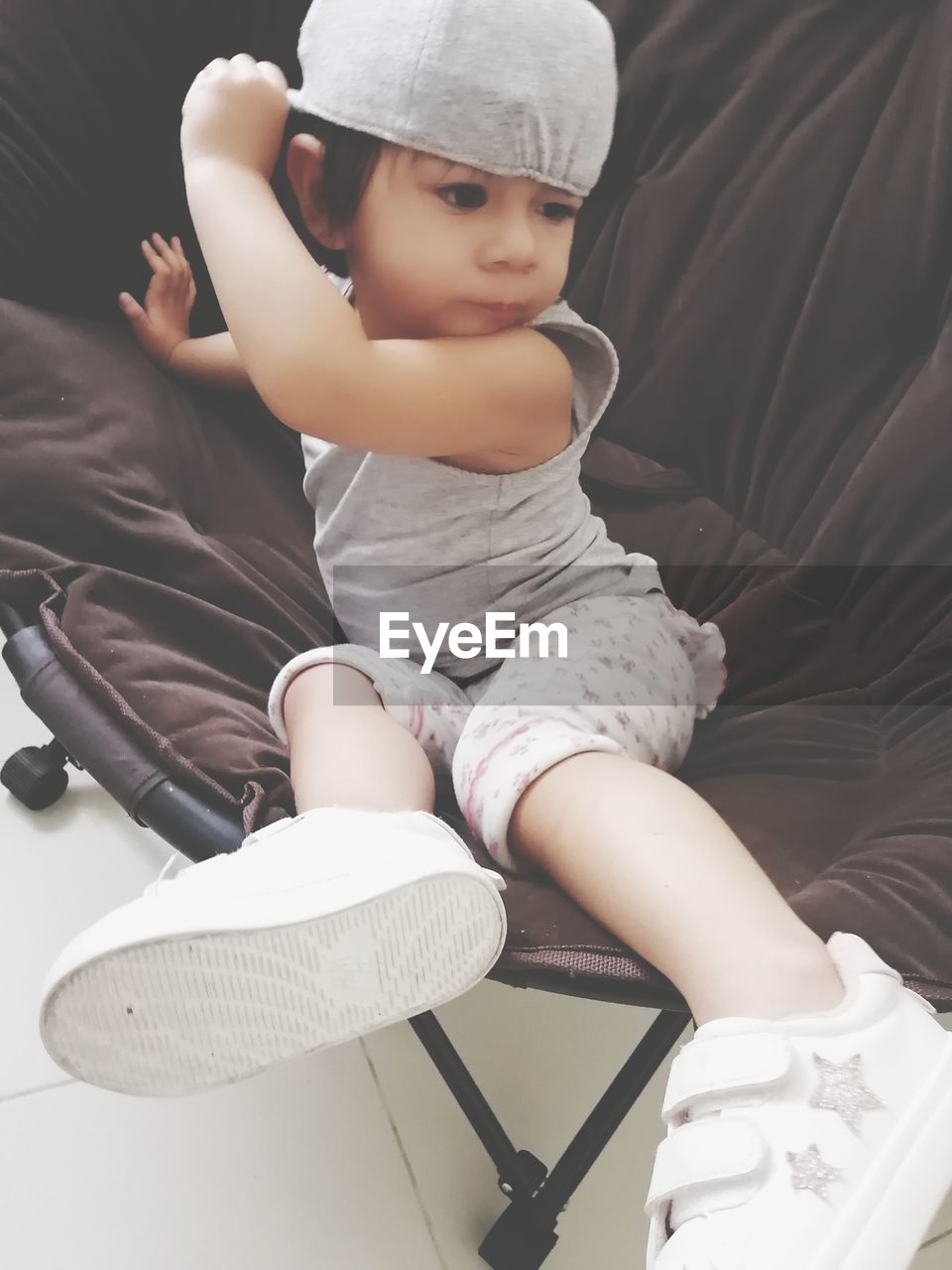 CUTE BABY GIRL SITTING ON SOFA IN BEDROOM