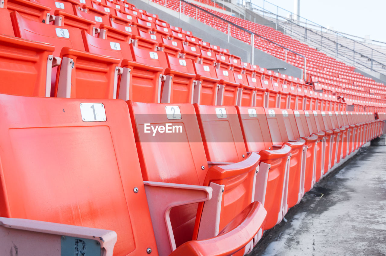 in a row, red, no people, architecture, transportation, order, transport, repetition, vehicle, large group of objects, industry, day, seat, outdoors, sport venue