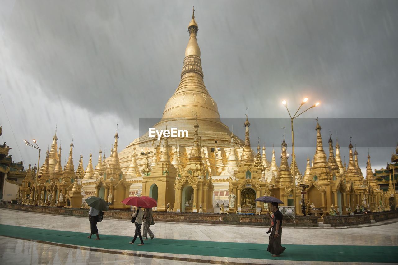 GROUP OF PEOPLE OUTSIDE TEMPLE AGAINST SKY