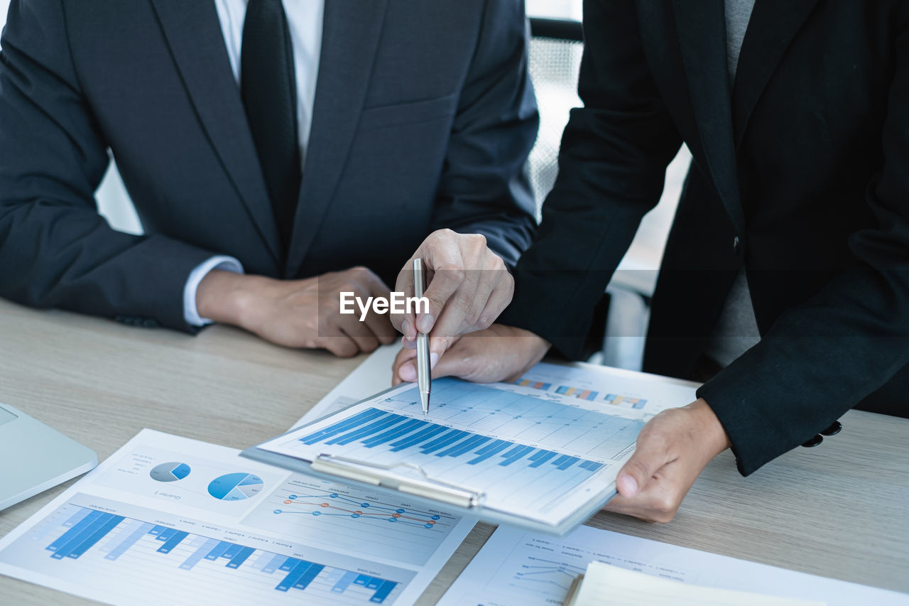 midsection of business people working at desk in office