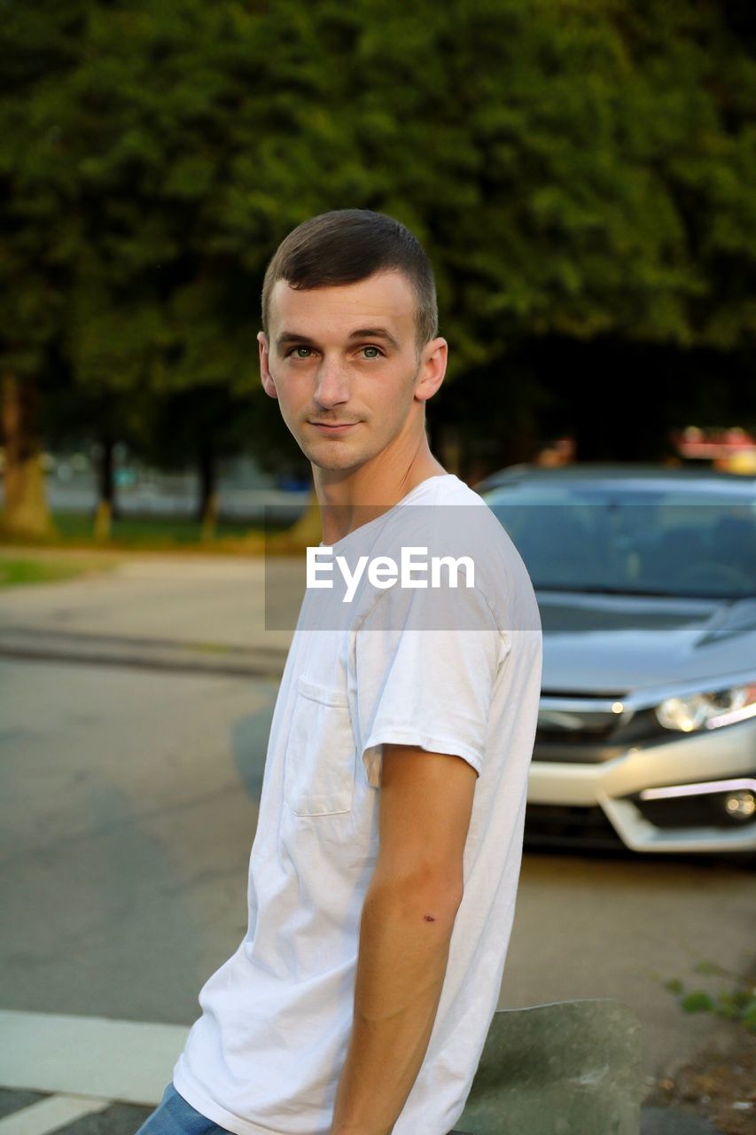 Portrait of young man standing on road