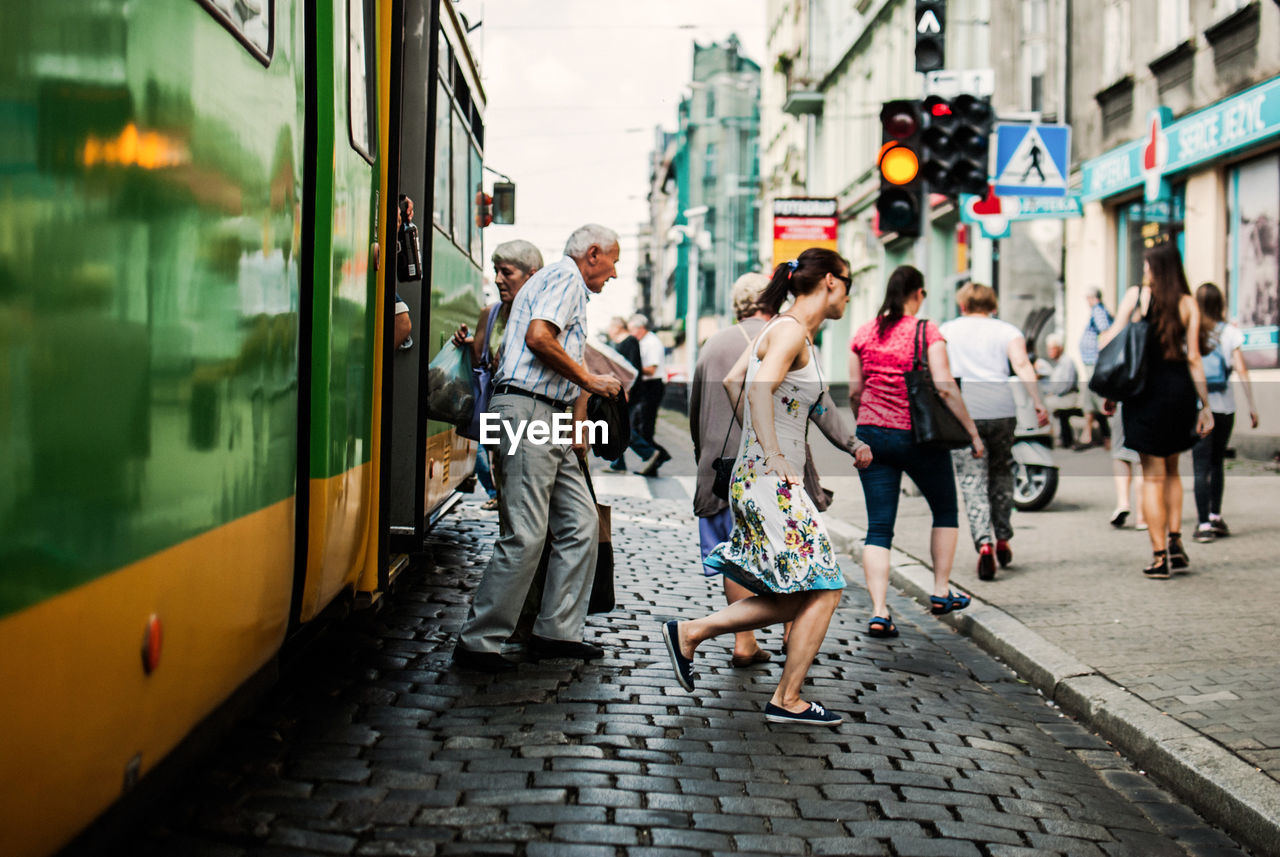 PEOPLE WALKING ON STREET AMIDST TRAIN