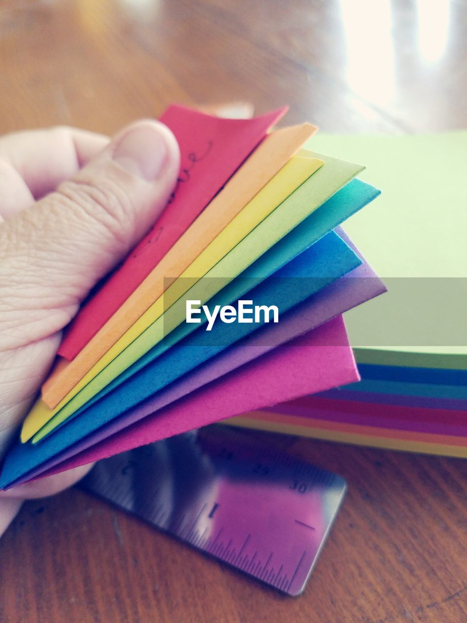 Cropped hand holding colorful adhesive notes on table